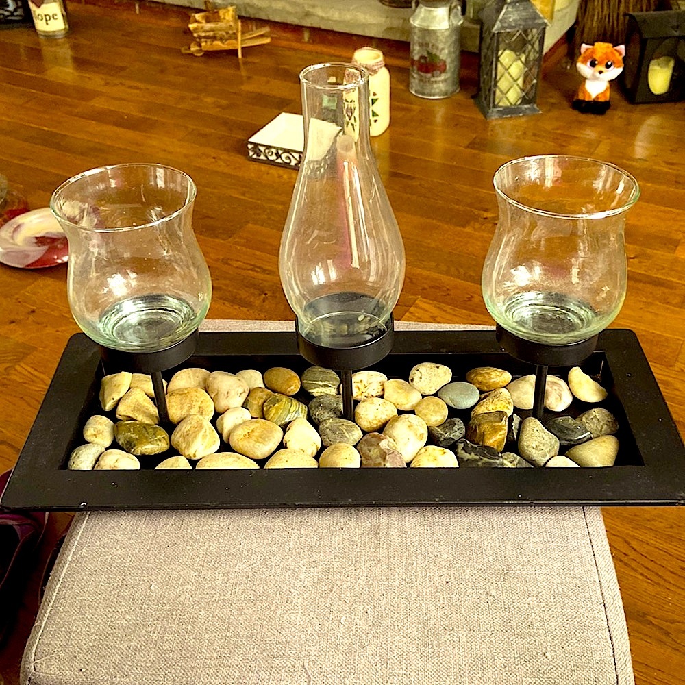 Three hurricane candle holders with rocks.